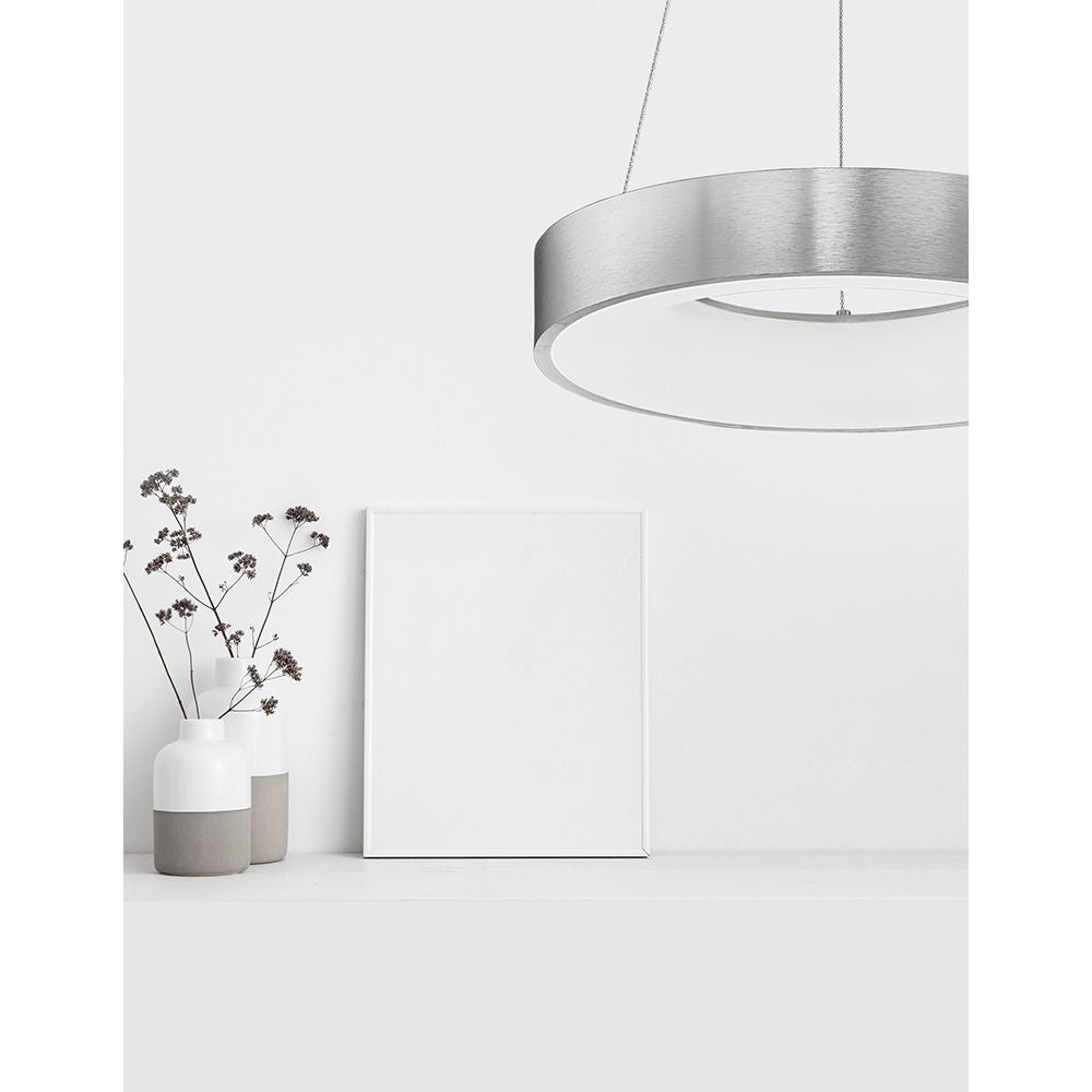 Moderne Rando LED Thin Hängelampe in Aluminium über einem Tisch mit Blumen und leeren Bilderrahmen.