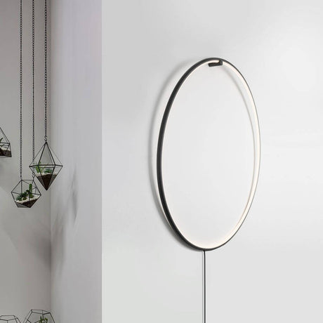 Ring LED-Wandleuchte zum aufhängen Schwarz an einer Wand mit hängenden Pflanzen daneben.
