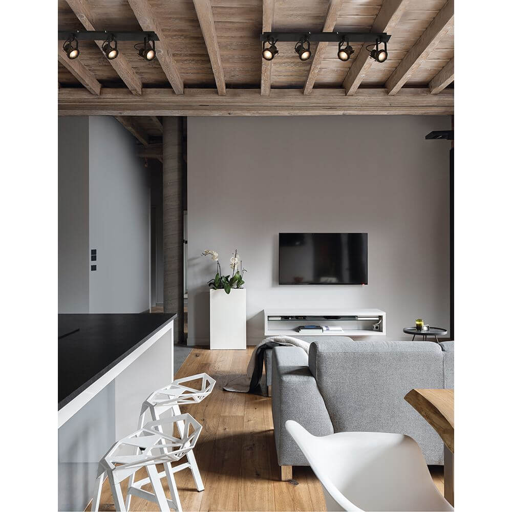 Salva Deckenstrahler 4-flammig Metall im modernen Wohnzimmer mit schwarzer Wand und Holzbalkendecke.