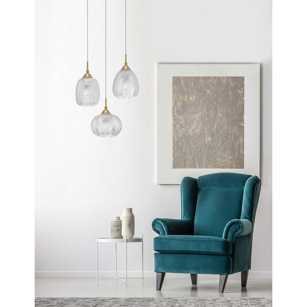 Vario Hängelampe 3-flammig Glas, Metall über einem blauen Sessel in einem modernen Wohnraum.