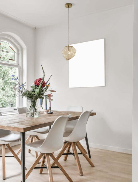 Suspension Odelle Ø 18 cm Or, Ambre au-dessus d’une table en bois avec des chaises dans une salle à manger moderne.