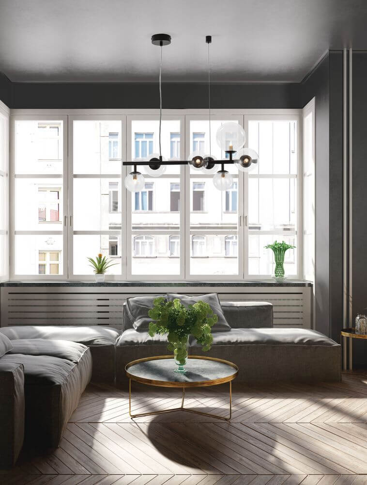 Moderne Wohnlandschaft mit Odillia Pendelleuchte G9 7-flammig über einem Couchtisch und großen Fenstern.
