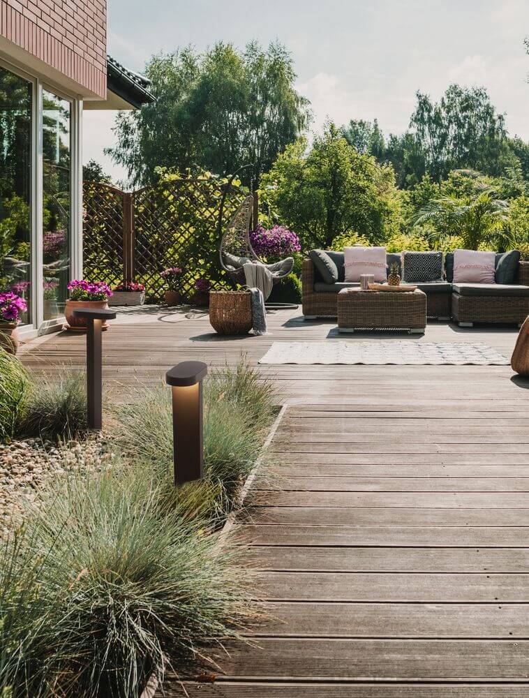 Moderne Ofir LED Außenwegeleuchte 3000K in schwarz auf einer Terrasse mit Garten.