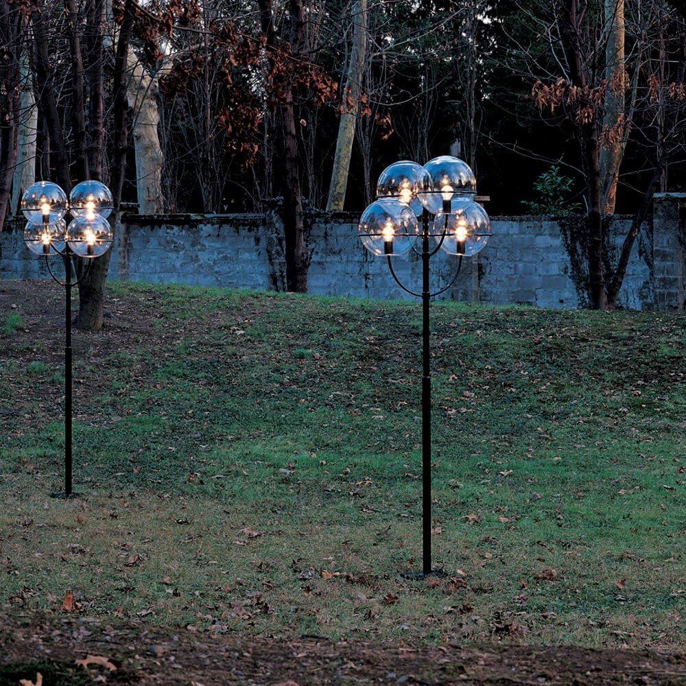 Oluce Außen-Laterne Stehlampe Lyndon 300 in Schwarz, beleuchtet im Garten unter Bäumen.