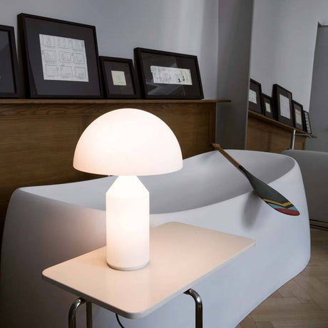 Oluce Glas Tischleuchte Atollo 35 Opal auf einem Beistelltisch in modernem Wohnraum.