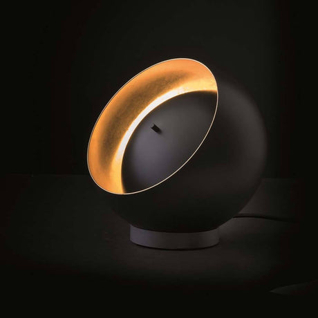 Oluce LED Tischleuchte Eva Schwarz, Goldfarben auf einem Tisch mit elegantem Design und einzigartiger Lichtwirkung.