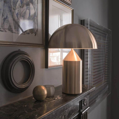 Oluce Tischlampe Atollo 70 Goldfarben auf einem Sideboard mit kunstvollen Rahmen und dekorativen Gegenständen.