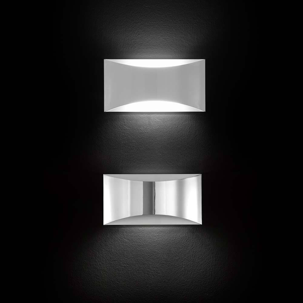 Oluce LED Wandleuchte Kelly Weiß in modernem Design, zwei elegante Leuchten an einer dunklen Wand.