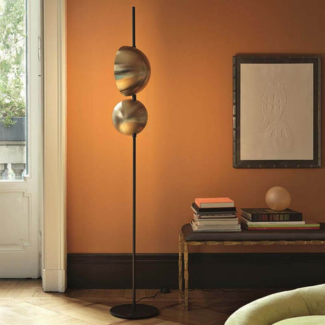 Oluce LED Stehleuchte Superluna Schwarz in modernem Raum mit orangefarbener Wand und kreativer Dekoration.
