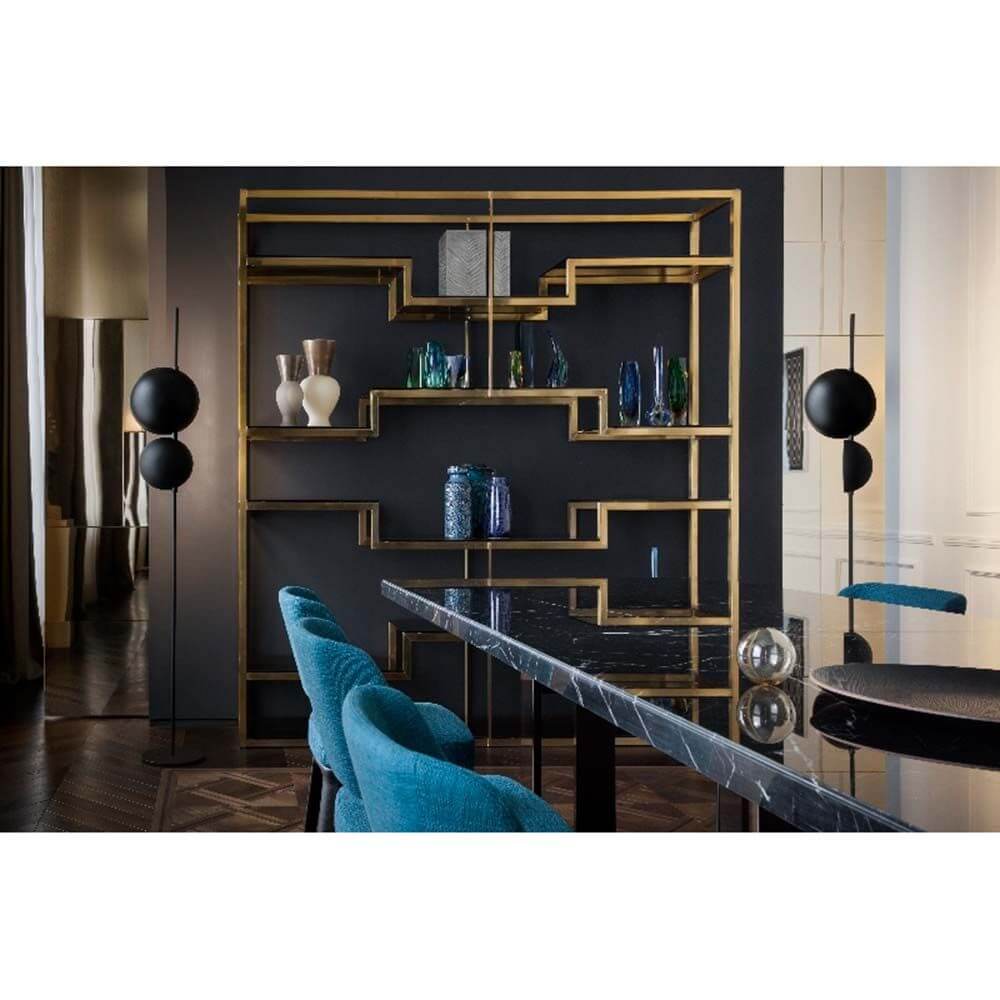 Modernes Regal aus Gold mit dekorativen Flaschen und stilvollem Essbereich in einem eleganten Raum.