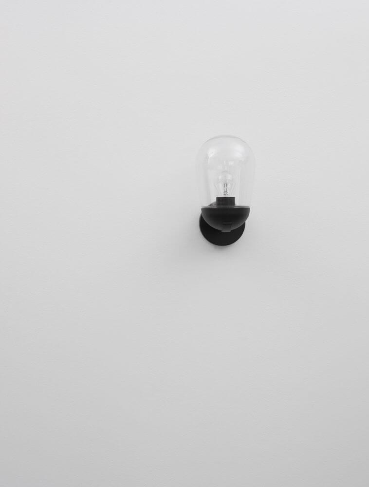 Omika Außenwandleuchte Dunkelgrau IP54 an einer weißen Wand montiert, modernes Design mit Glas und Aluminium.