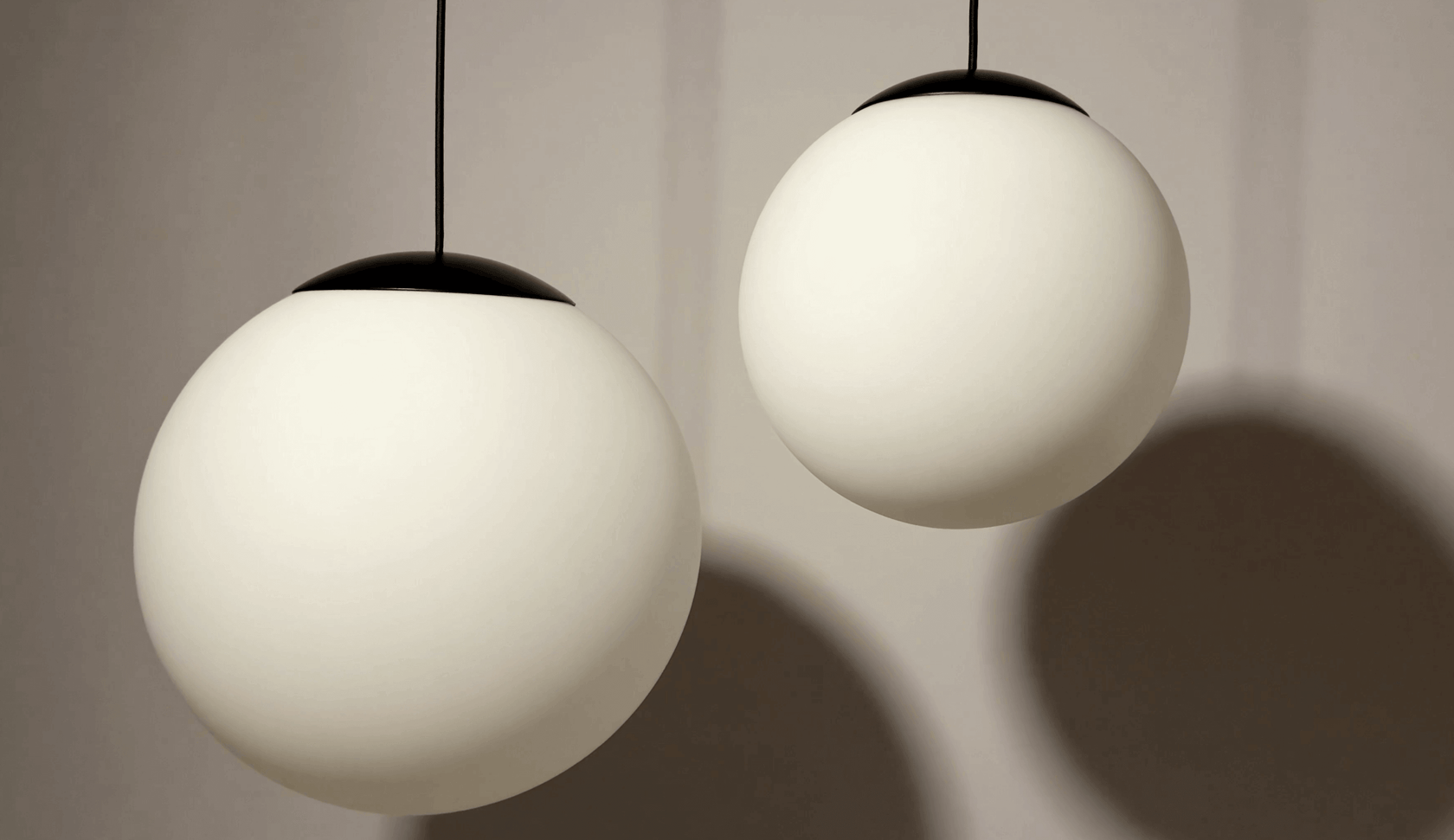 Moderne Pendelleuchten in Kugelform mit weißen Glaskugeln und schwarzem Metallaufsatz.