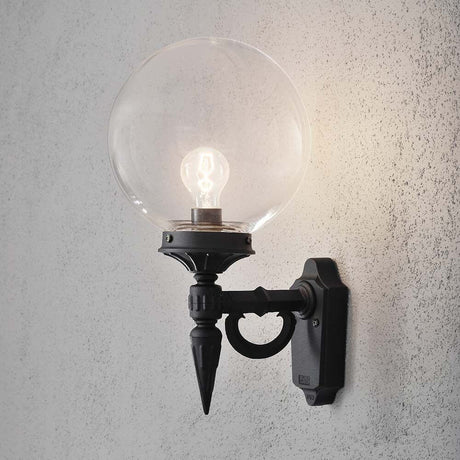 Orion Außen-Wandleuchte Schwarz, klares Acrylglas an einer Betonwand mit einer glänzenden Globenlampe.
