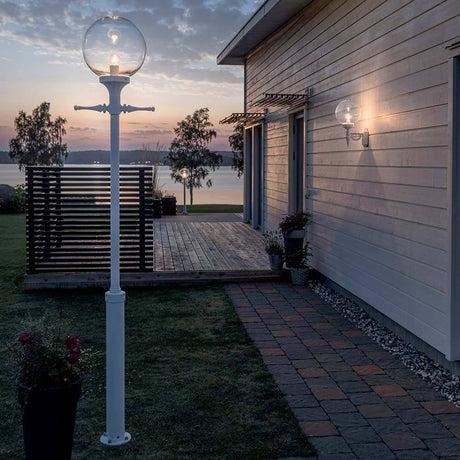 Orion golvlampa vit, klart akrylglas i trädgården vid skymning, modern belysning för utomhusområden.
