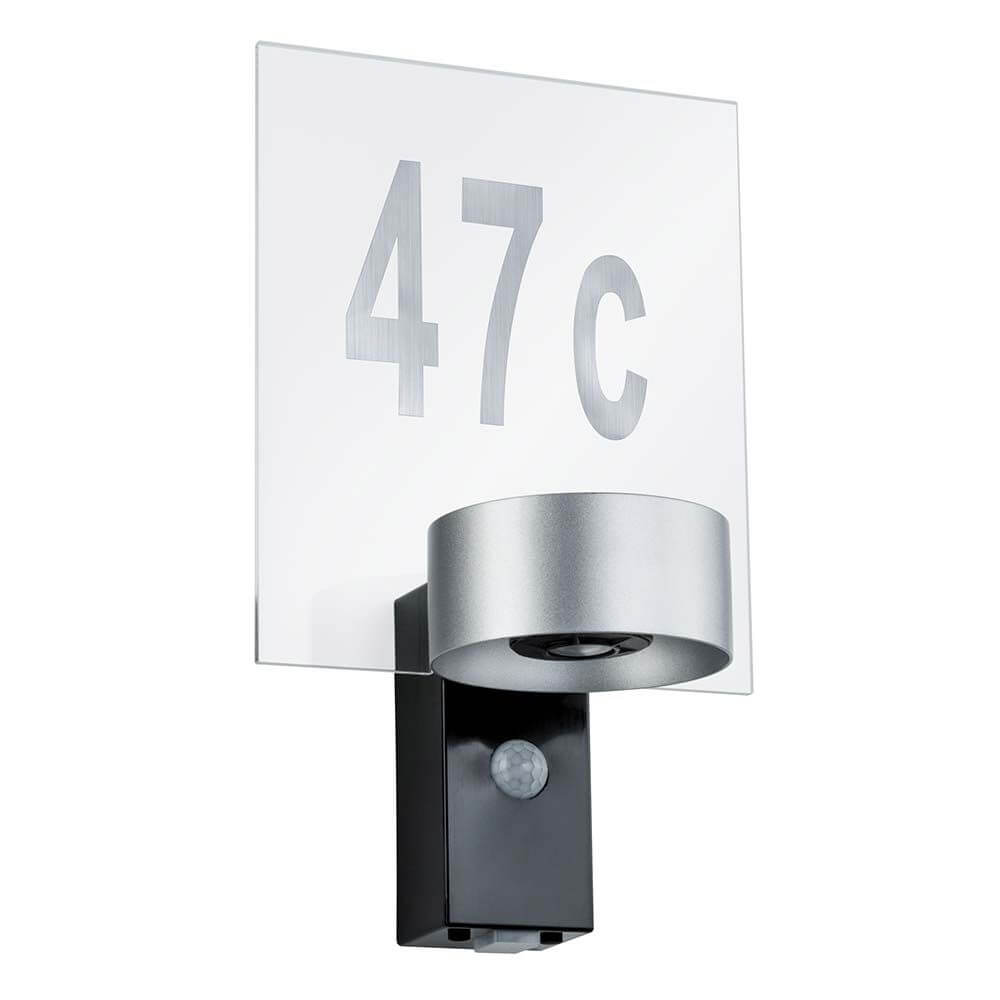 Hausnummernschild Outdoor House Transparent mit silbernem Nummernsatz und Wandleuchte im Eingangsbereich.