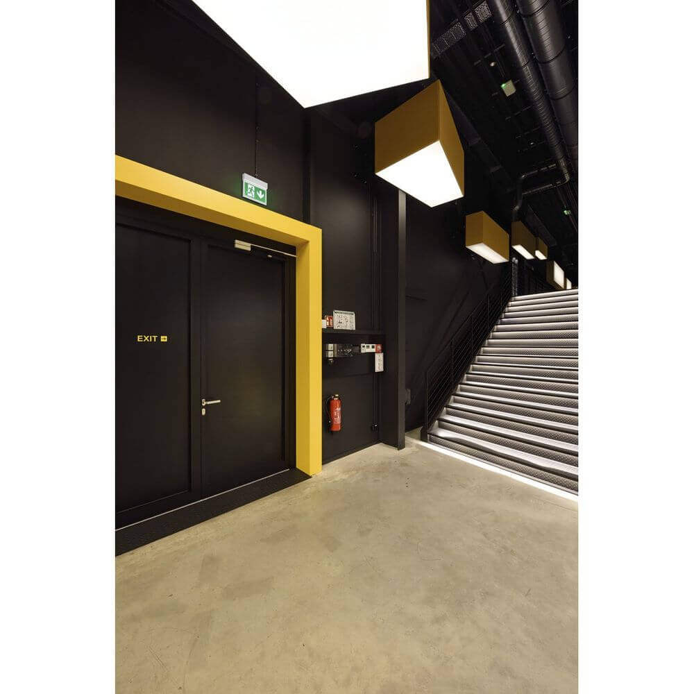 Notausgangsbereich mit Tür, Sicherheitslampen und Treppe in moderner Architektur.