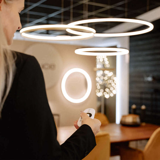 Frau mit Fernbedienung in modernem Raum mit runden Lichtern und stilvollem Interieur.
