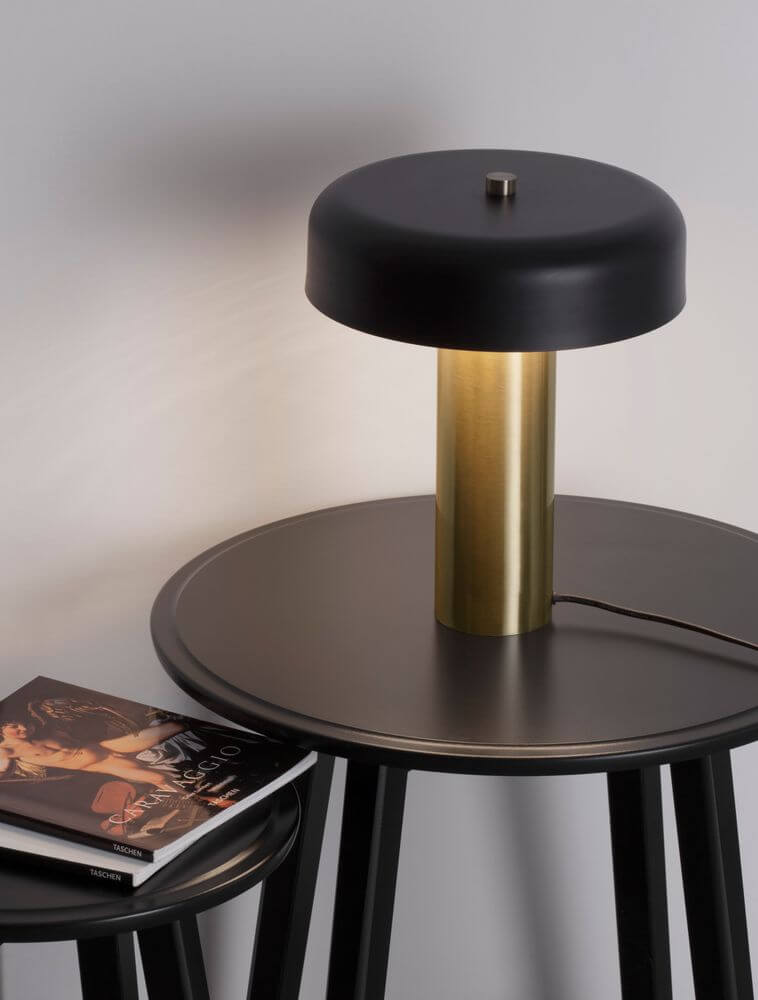 Pandora LED Tischleuchte 3000K Schwarz, Gold auf einem Tisch mit Büchern.