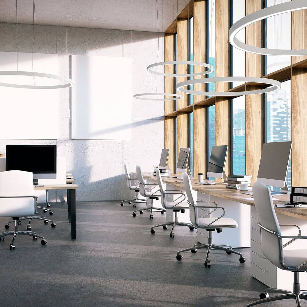 Moderne Büroumgebung mit Panzeri Brooklyn LED-Ring Pendelleuchte über Schreibtischen.