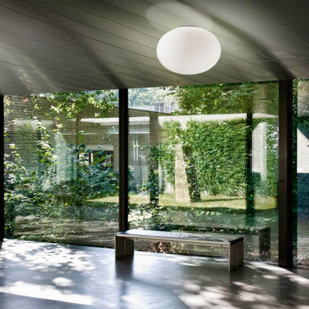 Panzeri Gilbert Glas Deckenleuchte in modernem Raum mit großen Fenstern und Blick ins Grüne.
