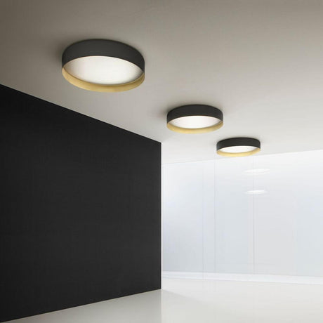 Panzeri Ginevra LED Guld loftslampe i et moderne rum med sorte og guld accenter.
