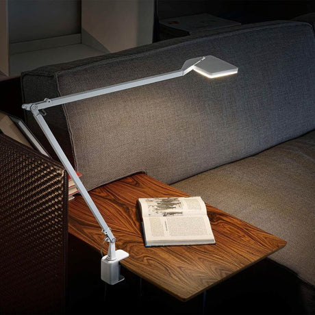 Panzeri Jackie justerbar LED-bordlampe med berøringsdimmer på et bord med bok.