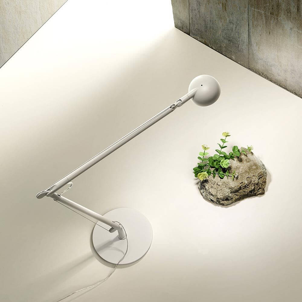 Panzeri Opuntia LED-Schreibtischlampe CCT-Dimmbar in modernem Design auf einem Tisch mit Pflanze.