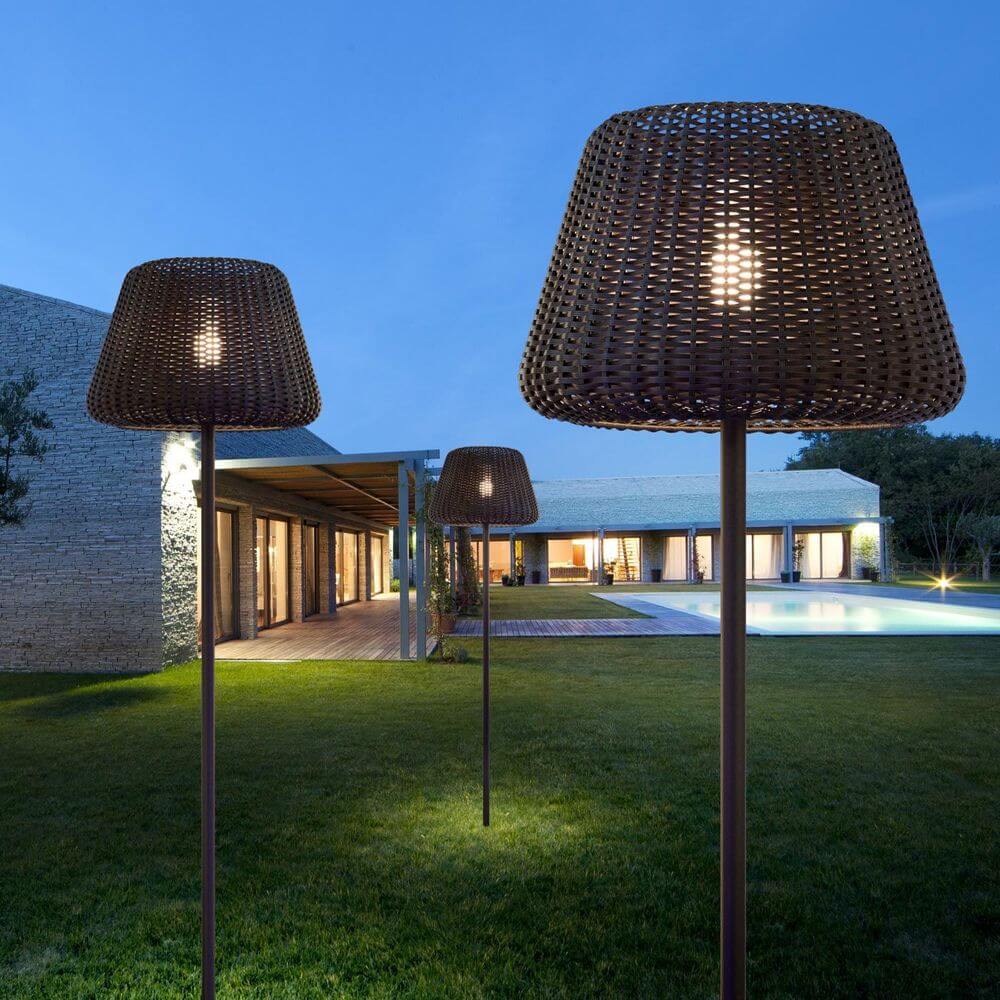 Panzeri Ralph Stehleuchte aus synthetischem Rattan, ideal für Garten und Terrasse, bei Dämmerung erleuchtet.