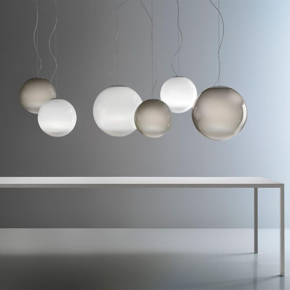 Panzeri Smoke Glas-Pendellampe mundgeblasen in verschiedenen Größen, elegant und mystisch auf einem Tisch arrangiert.