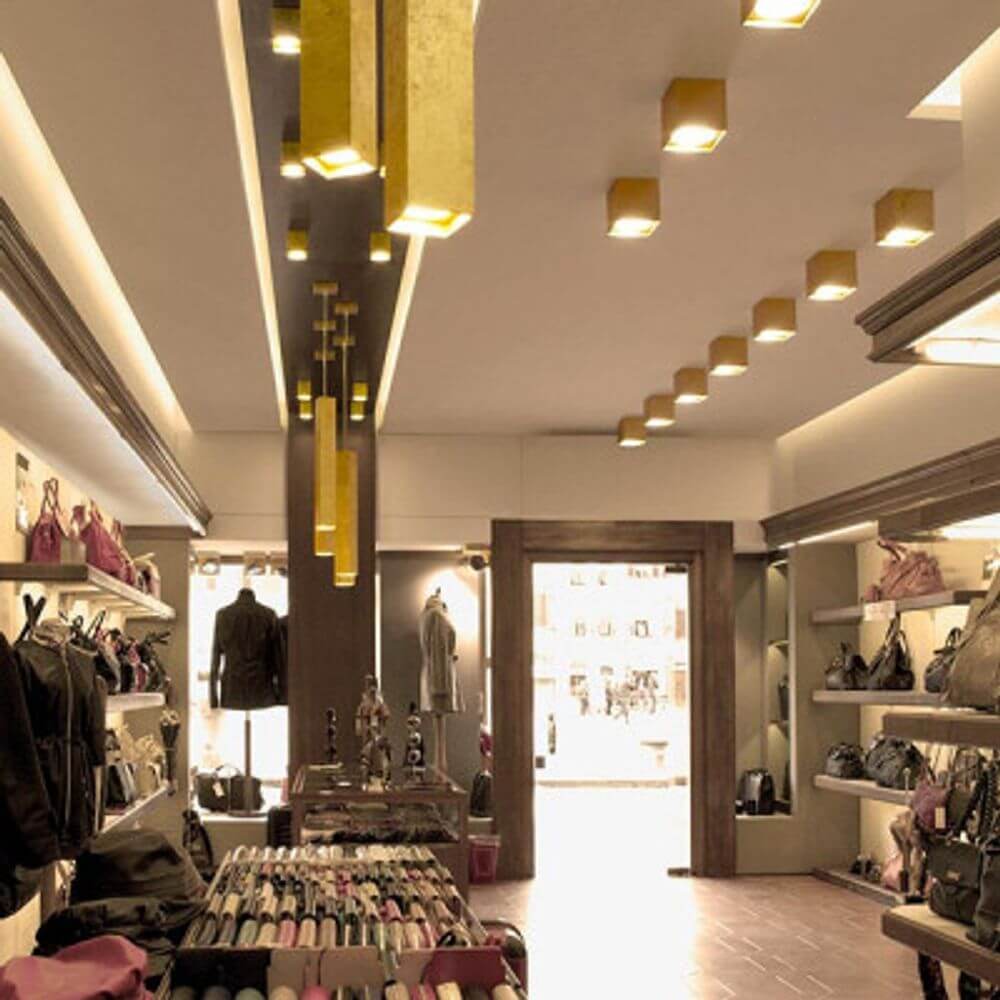 Moderne LED-Pendelleuchten aus Aluminium in Goldfarbtönen in einem eleganten Geschäft für Taschen.