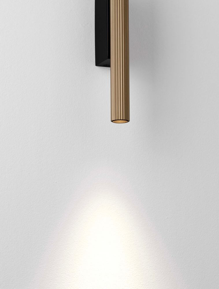 Paron LED Wandleuchte Geriffelt 3000K mit goldfarbenem Aluminiumkorpus und matte schwarze Basis.