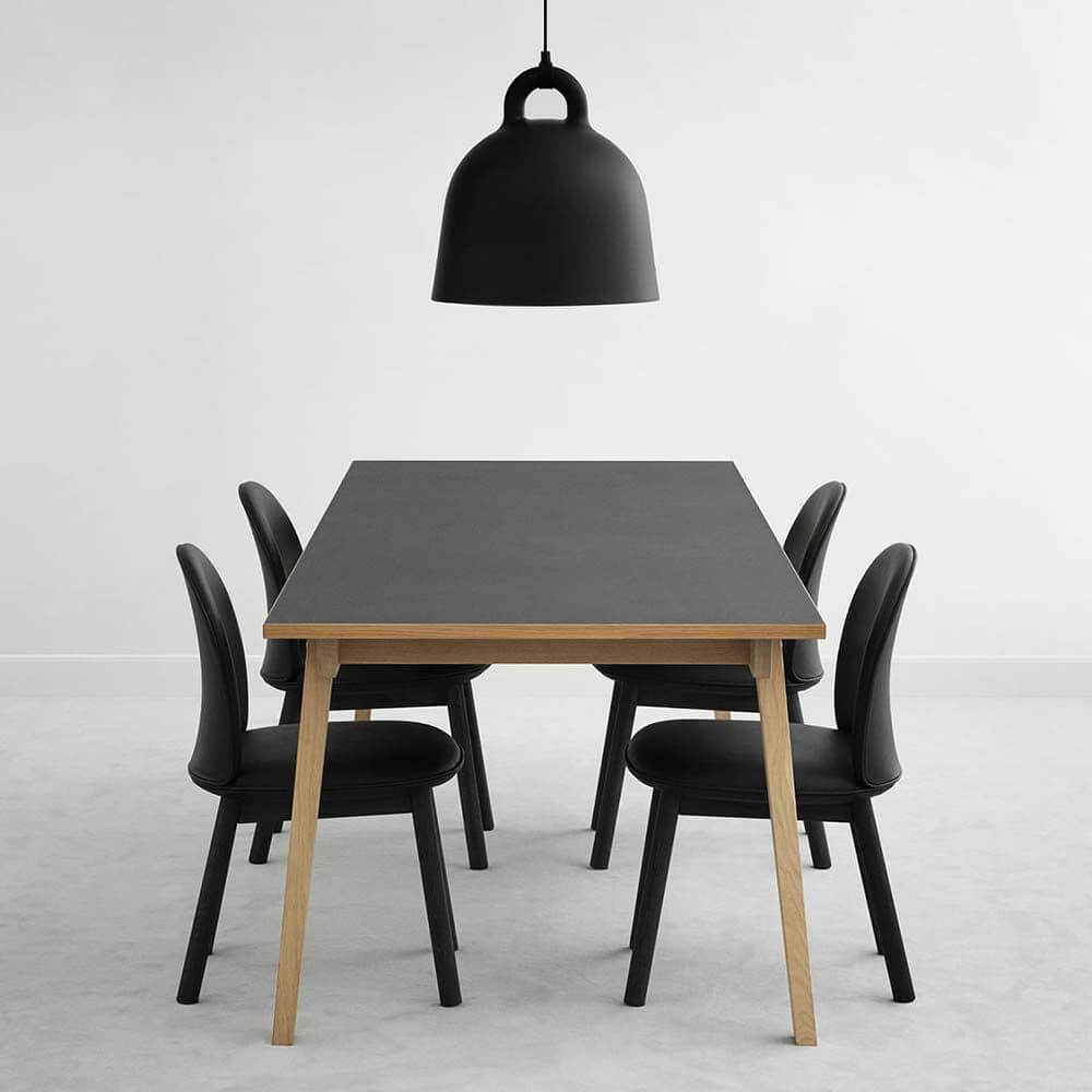 Pendelleuchte Bell M Ø 42cm Schwarz über einem modernen Esstisch mit schwarzen Stühlen.