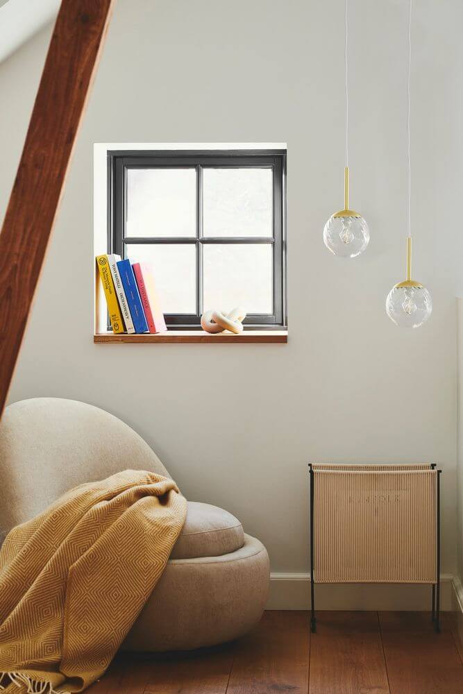 Pendelleuchte Chisell 15 in modernem Raum mit Fenster und Bücherregal.