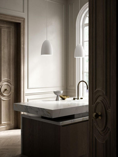 Pendelleuchte Nexus 2 in modernem Badezimmer mit marmoriertem Waschbecken und eleganter Holzverkleidung.
