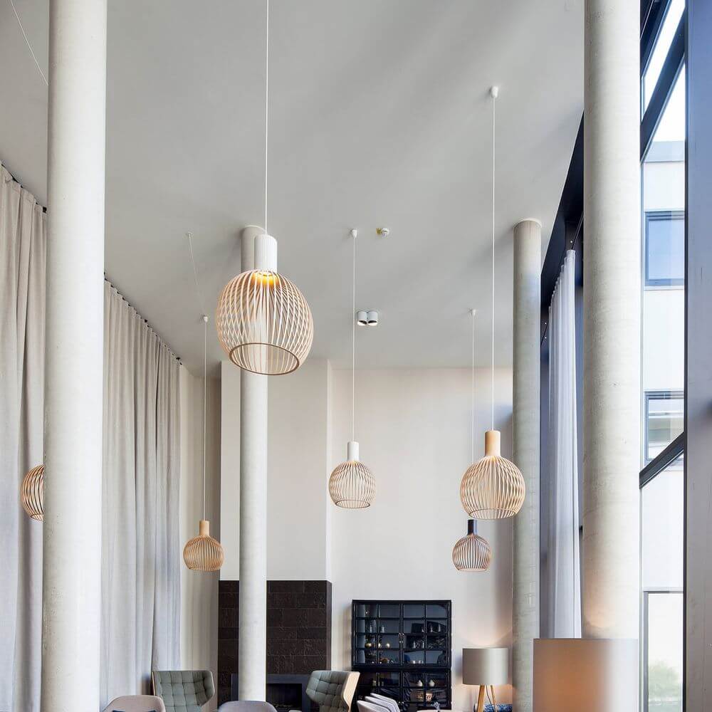 Moderne Pendelleuchten aus Holz im eleganten Wohnraum mit weißen Wänden und Säulen.