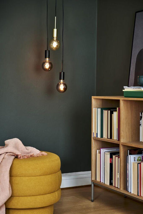 Pendelleuchte Paco 3-Spot in minimalistischer Einrichtung mit brassfarbigen Leuchtmitteln und bookshelf.