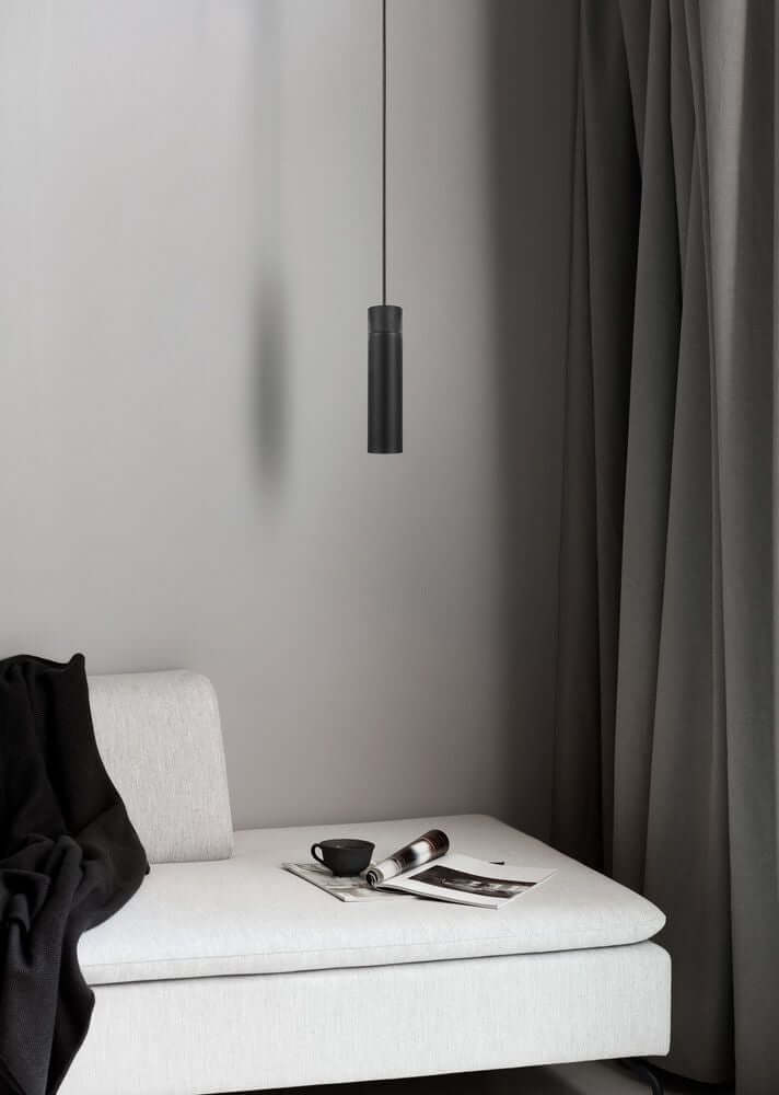 Pendelleuchte Tilo in skandinavischem Design über einer modernen Couch mit Kissen und Zeitschriften.