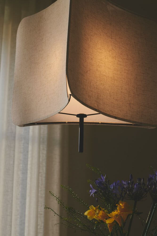 Pendelleuchte Tinto mit modernem dreieckigem Schirm und elegantem Design über einem Tisch.
