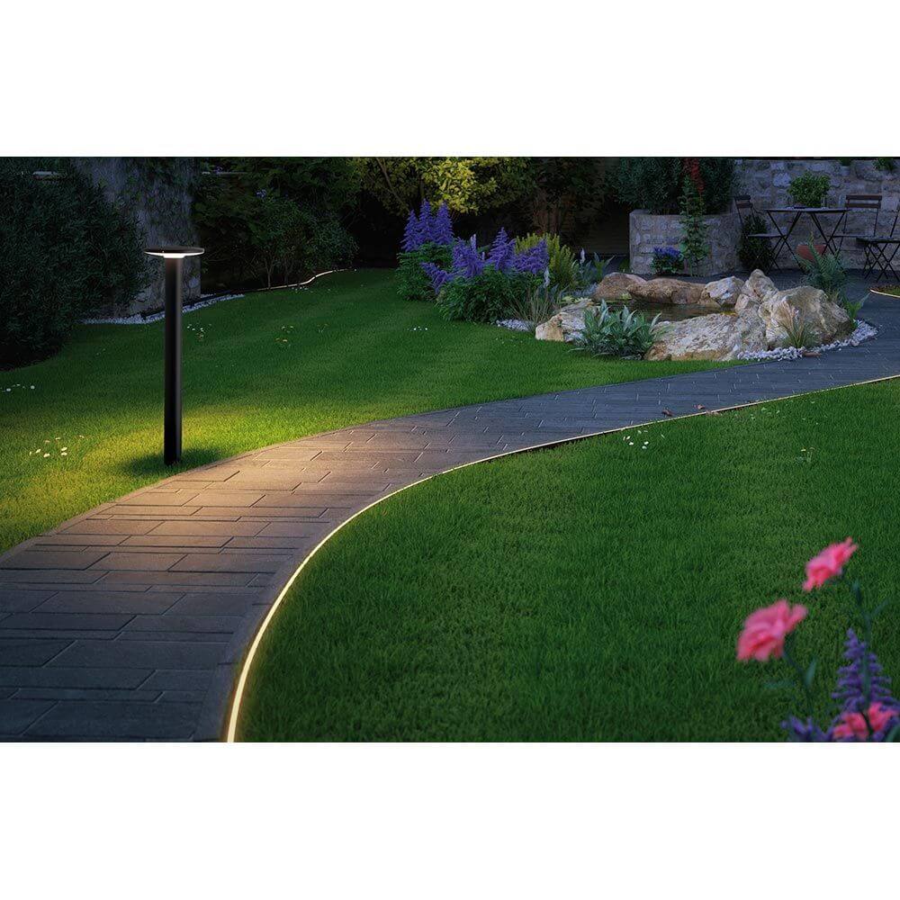 Plug & Shine LED Pollerleuchte Plate Anthrazit beleuchtet den Gartenweg und die Umgebung bei Nacht.