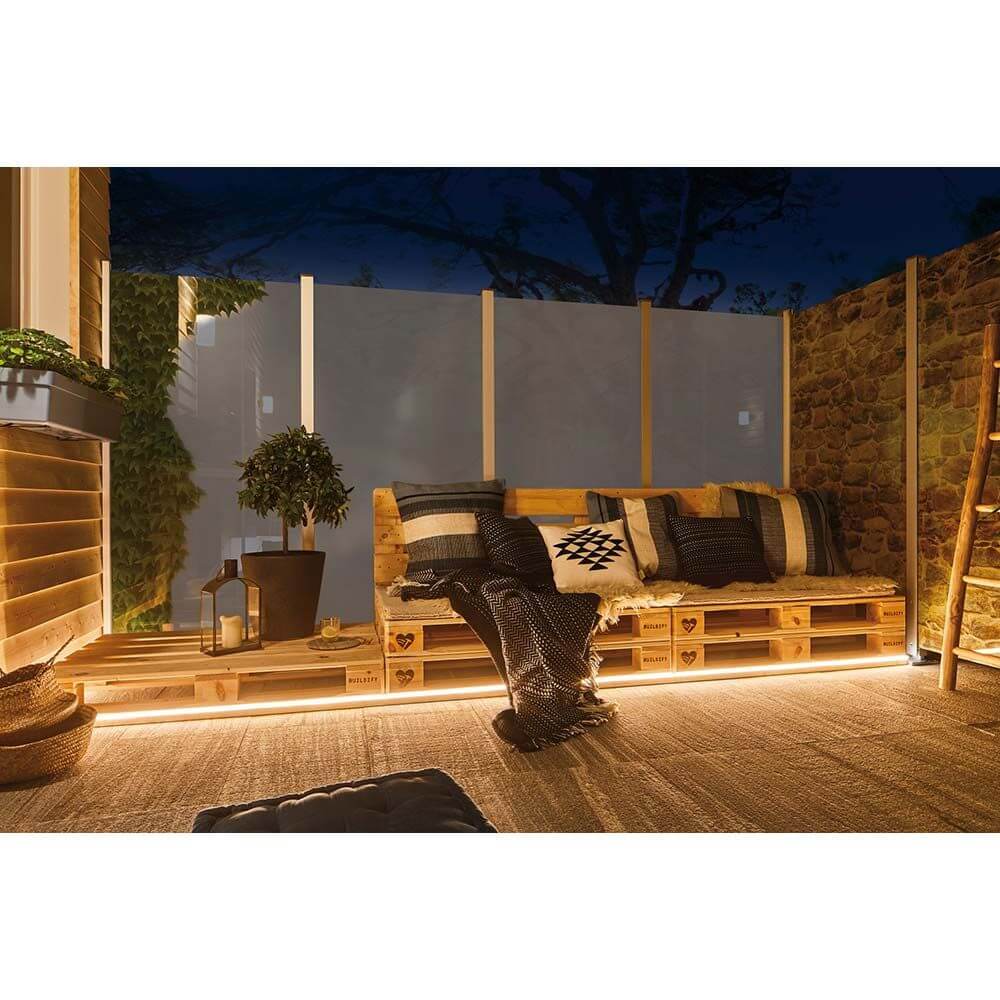 LED Plug & Shine Neon Stripe IP67 3000K 5m beleuchtet eine gemütliche Sitzecke mit Palettenmöbeln und Pflanzen.