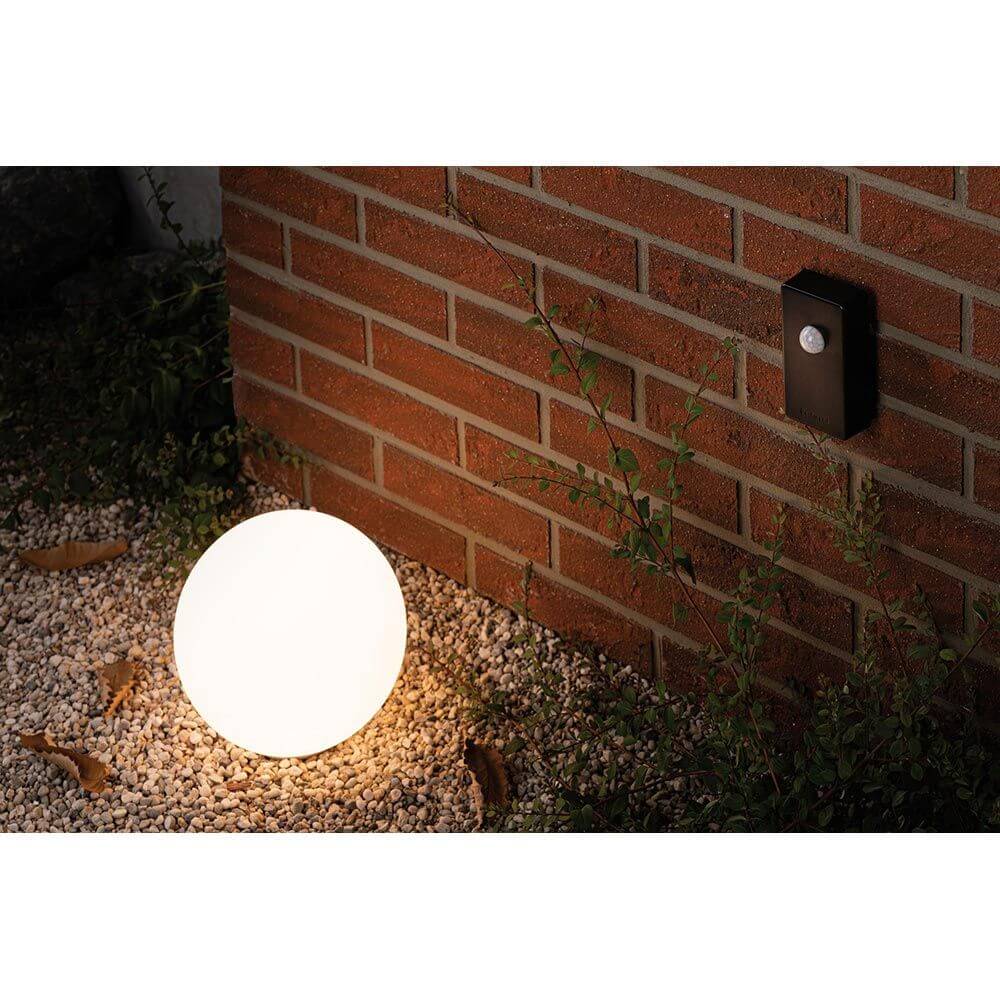 Plug & Shine Smart Home Zigbee Dämmerungssensor Anthrazit und schlichte Gartenleuchte im Außenbereich.