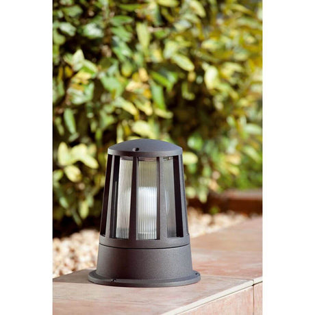 Modern SURAT IP54 dark grey bollard light in the garden next to green plants