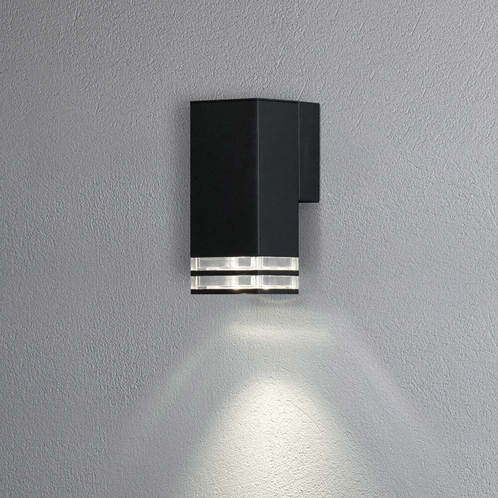 Pollux Außen Wandleuchte IP44 in Schwarz an einer grauen Wand installiert, mit elegantem Lichtstrahl.