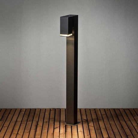 Pollux Pollerleuchte in Schwarz auf Holzterrasse, modernes Design mit GU10 Sockel.