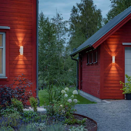 Pollux Wandleuchte 2-flammig an rotem Holzhaus, stilvolle Außenbeleuchtung für Garten und Fassade.