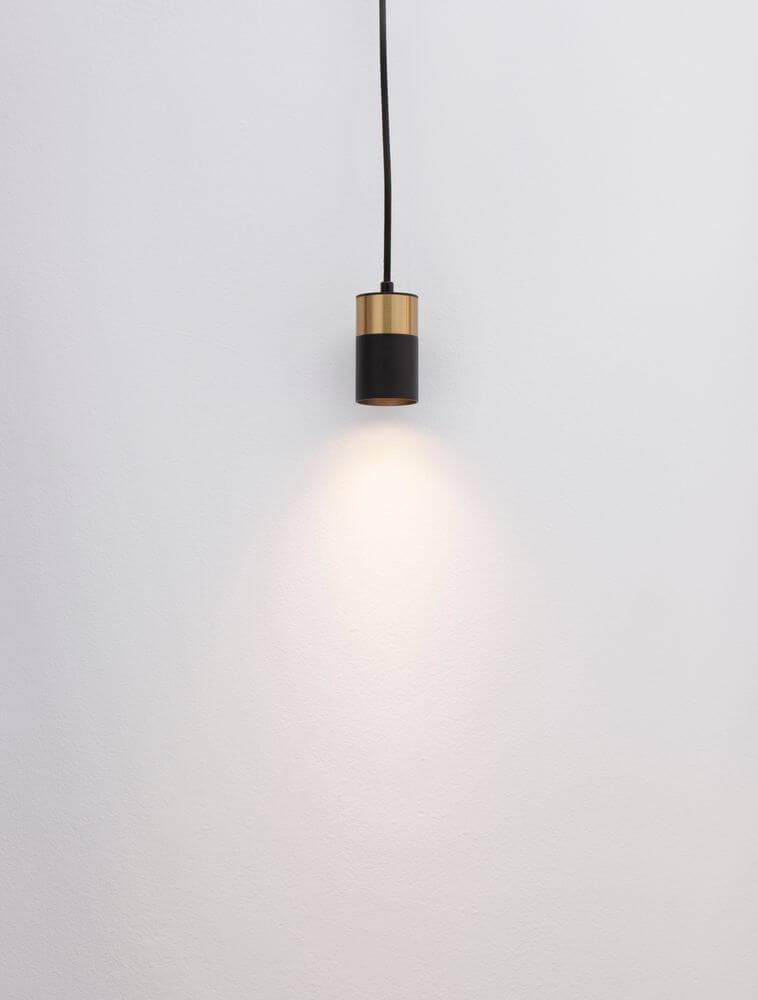 Pongo Pendelleuchte Cover Unten Ø 5,6cm Schwarz, Gold an einer Wand montiert, strahlt sanftes Licht.