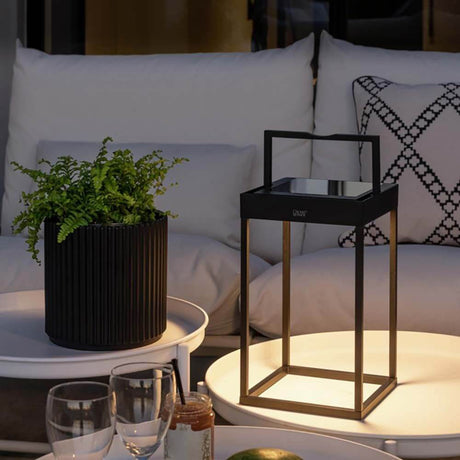 Portofino LED Solar floor light IP54 on a table with plants and glasses in a cozy outdoor area.