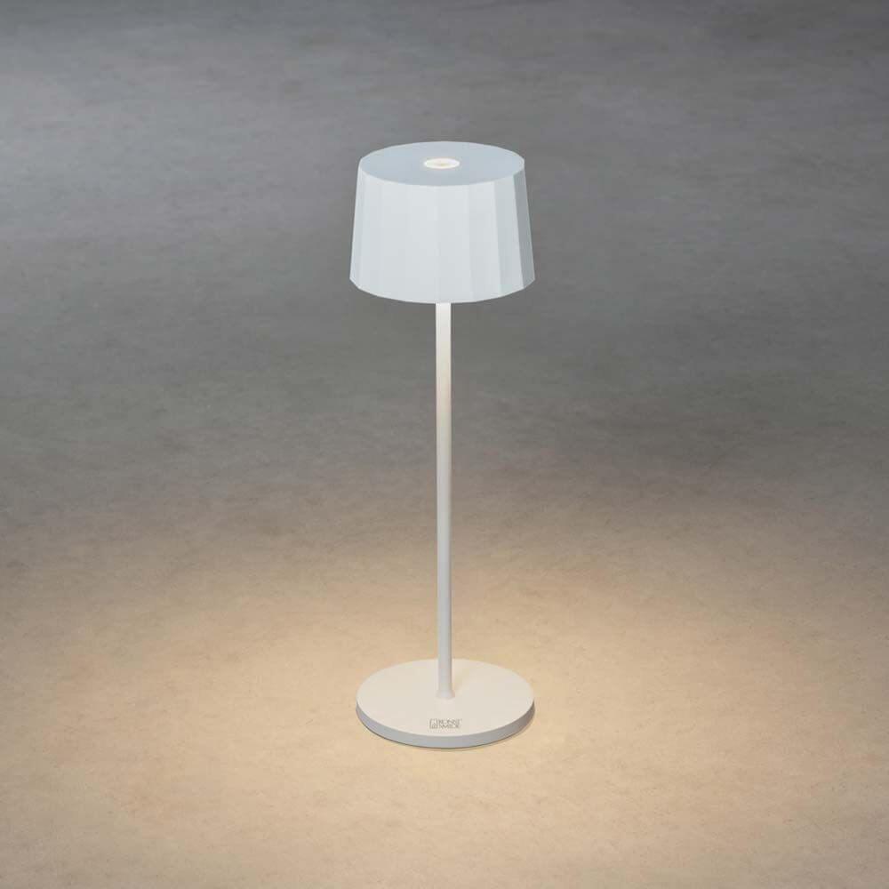 Positano Outdoor LED Akku Tischleuchte auf einem Schreibtisch mit dimmbarem Licht in neutralem Design.