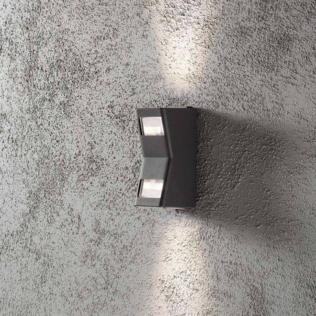 Lâmpada de parede exterior Potenza Up & Down Antracite IP54 instalada numa parede rugosa para iluminação exterior.