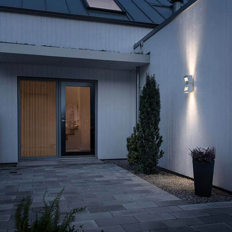 Potenza utendørs vegglampe hvit, klart akrylglass lyser på veggen til et moderne hus.